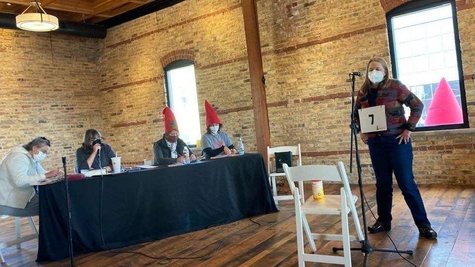 Kellie Monroe Aquino stands before a panel of judges at the Adult Spelling Bee.