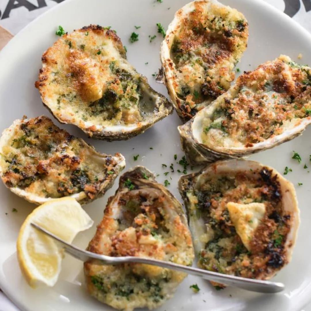 Baked Oysters with a fork that has a lemon on it. 