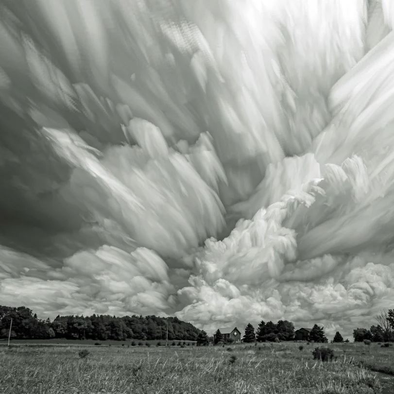 'Storm at Wilke Prairie Preserve' by Mark Weller, the picture shows menacing storm clouds over a peaceful prairie in black and white.