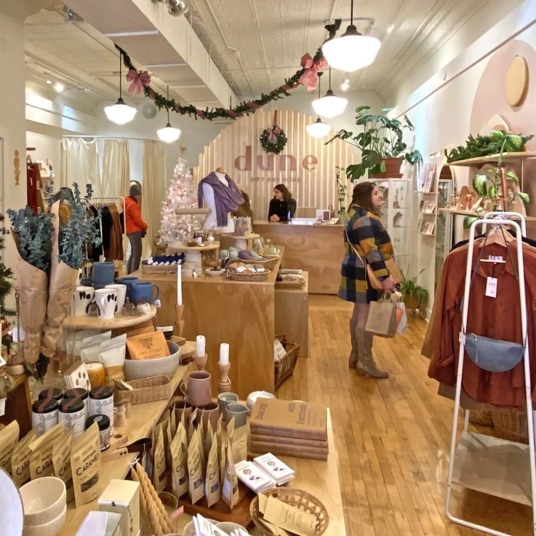 Image of a woman shopping at Dune, with displays filled with items.