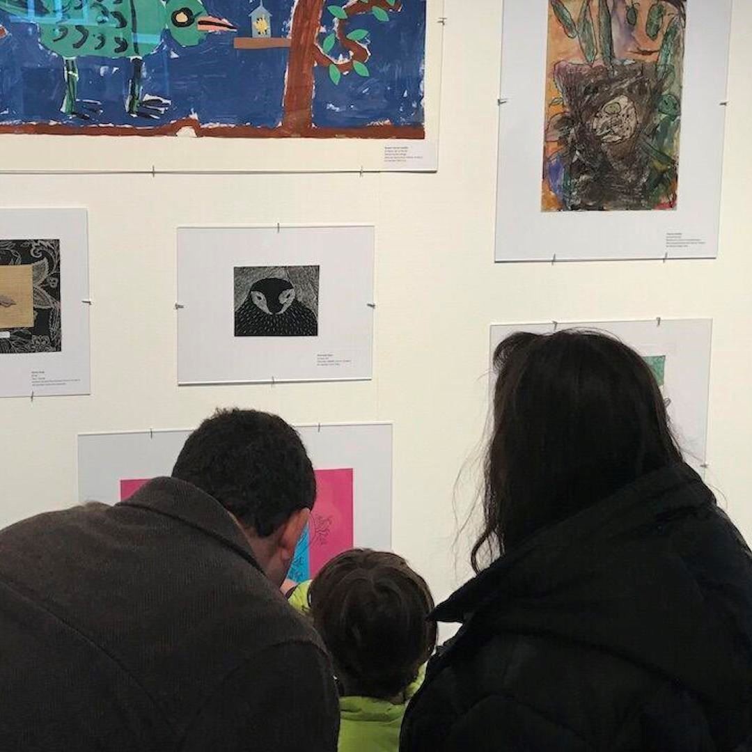 Parents looking at art with their child in front of them