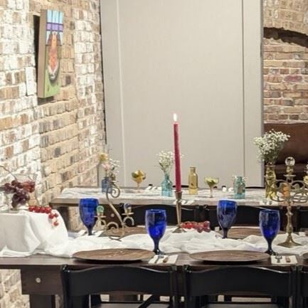A dinner table set with blue cups and candlesticks.