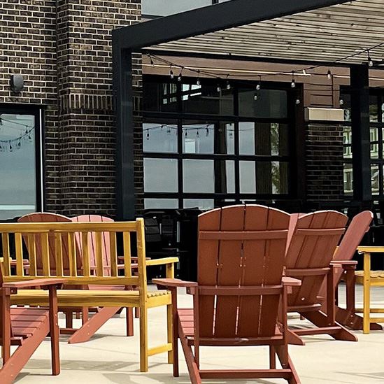 A picture of a patio with Adirondack chairs and wood benches.