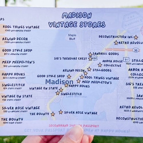 An individual holds up a Madison Vintage Stores Summer Passport. 